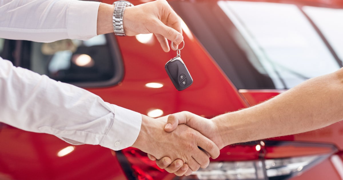 Image of a person giving the vehicle key to customer in the dealership